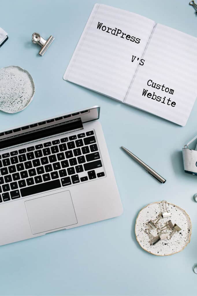 Computer on desk, blue background writing saying "wordpress V's Custom website