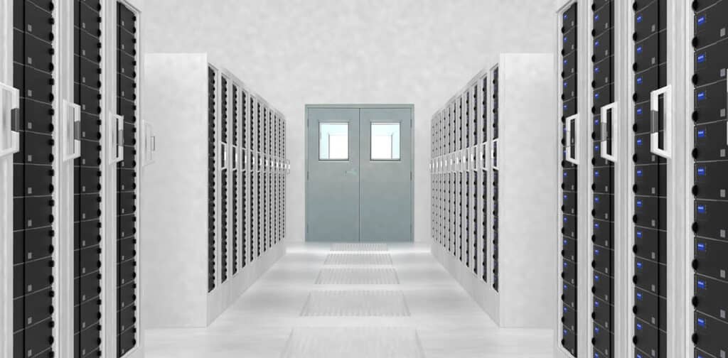 Large white room full of computer web host servers and a metal door at the end of the corridor. 