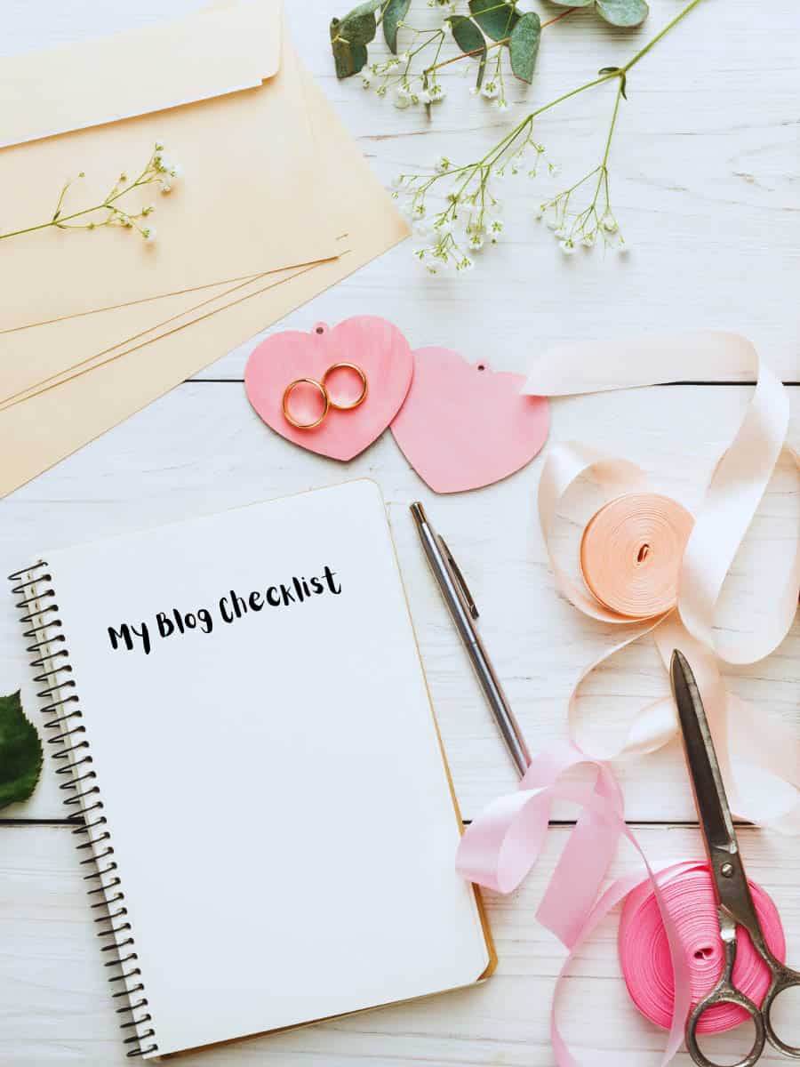Launching a blog checklist written on note book with craft supplies on a desk.